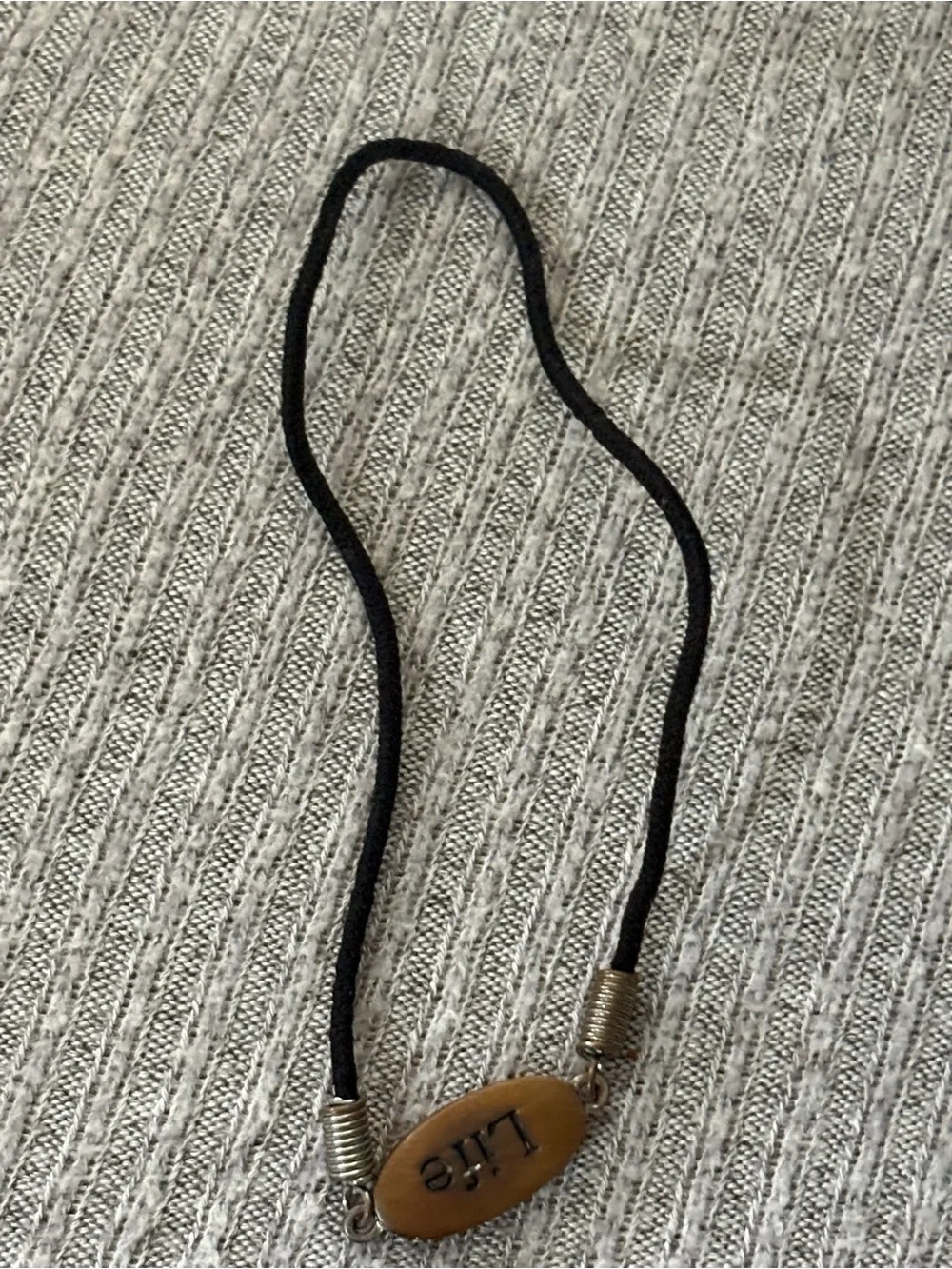 Black cord stretch bracelet w brown colored oval “Life” plaque